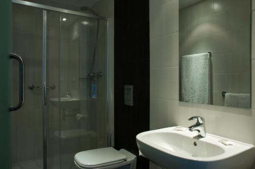 a bathroom with a sink and a shower and a toilet at Hotel Genesis in Fátima