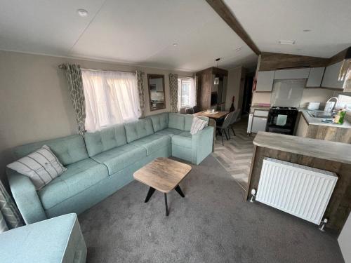 a living room with a blue couch and a kitchen at Royal Oak Caravan Park in Skegness