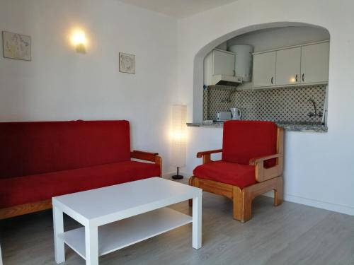 a living room with a red couch and a red chair at Oura Parque Apartamentos Turisticos in Albufeira