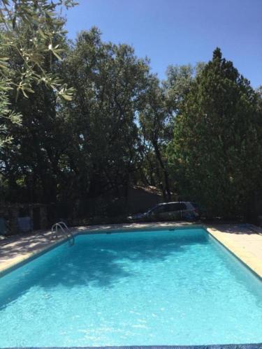 une grande piscine bleue avec des arbres en arrière-plan dans l'établissement Gite hameau de pomples, à Cabasse