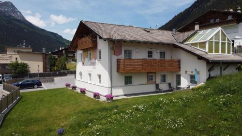 ein weißes Haus mit einem Holzdach und einem Hof in der Unterkunft Residence Dilitz in Reschen