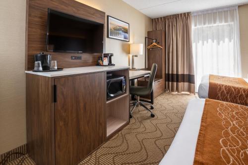 Habitación de hotel con cama y escritorio con TV. en Comfort Inn Lakeshore en North Bay