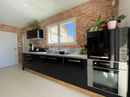 a kitchen with black appliances and a brick wall at LA BASTIDE DU SOLEIL avec piscine, calme, randonnée à proximité in Allegre Les Fumades