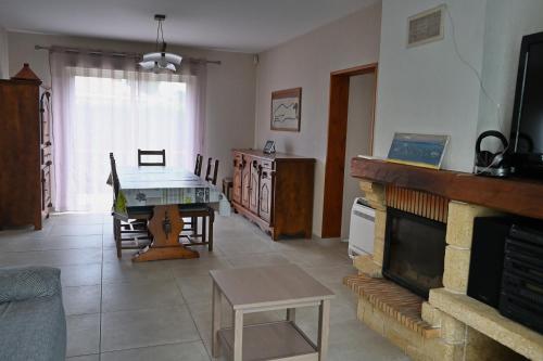 salon ze stołem i kominkiem w obiekcie Maison chaleureuse w mieście Lège-Cap-Ferret