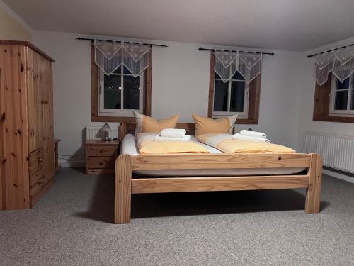 a bedroom with a wooden bed and two windows at Restaurant & Pension Forsthaus Hain in Kurort Oybin