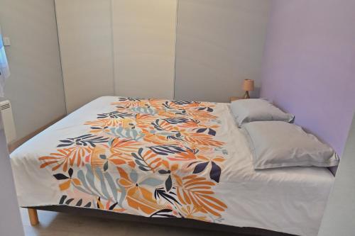 sypialnia z łóżkiem z kolorową kołdrą w obiekcie Maison chaleureuse w mieście Lège-Cap-Ferret