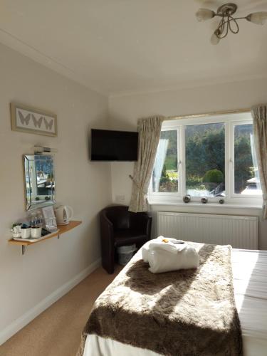 a bedroom with a bed and a chair and a window at Glenwood Guesthouse Betws-y-coed in Betws-y-coed