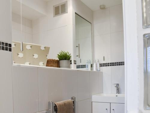 uma casa de banho branca com um lavatório e um espelho em High View em Truro