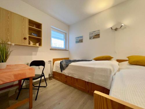 two beds in a room with a table and a desk at Haus am Deich Wohnung 13 in Dahme