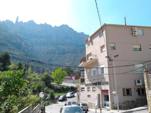 a building with cars parked on a street with mountains in the background at Guilleumes Montserrat in Monistrol