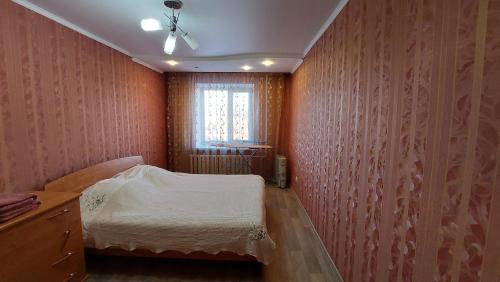 Habitación pequeña con cama y ventana en 2 комнатная квартира, en Shchūchīnsk