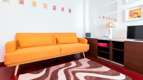 um sofá laranja numa sala de estar com uma televisão em Italianway - Nona Strada 7 em Segrate