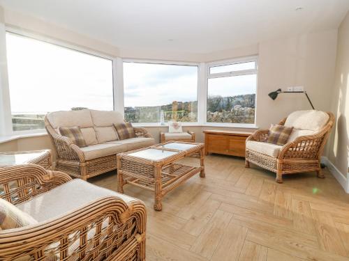 a living room with wicker furniture and large windows at Ty Top in Llanfaethlu