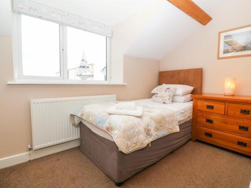 a bedroom with a bed and a window and a dresser at Ty Top in Llanfaethlu