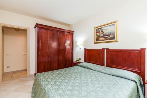 una camera con letto e testiera in legno di Regina Elena Apartments a Olbia