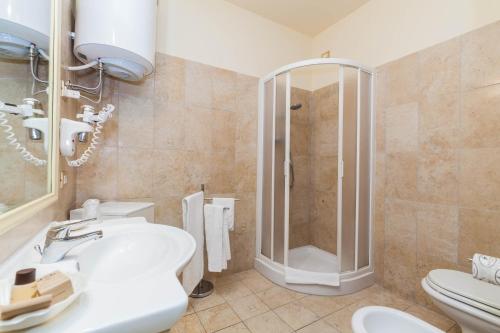 uma casa de banho com um chuveiro, um lavatório e um WC. em Regina Elena Apartments em Olbia