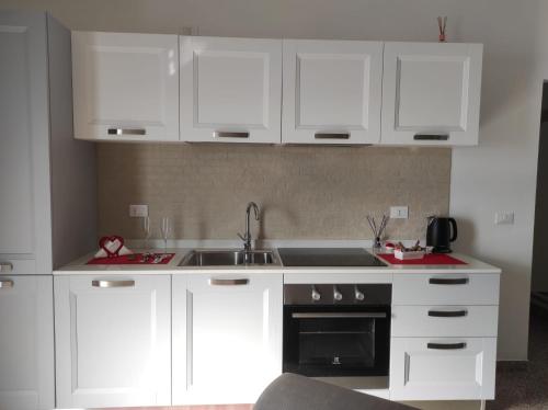 a kitchen with white cabinets and a sink at Red Tower Venice Apartment - 2 mins from VCE Airport- free Wifi in Tessera