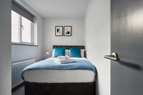 a bedroom with a bed with blue pillows and a window at Holborn by Viridian Apartments in London