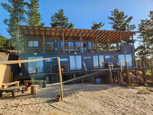 a large house with a wooden roof on a beach at Maravillosas Vistas Boyeruca Lodge in Vichuquén