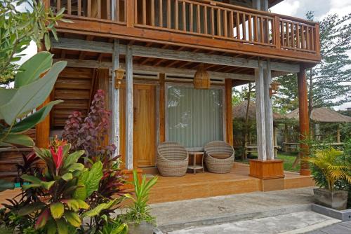 a house with a balcony with a table and chairs at Peraja Bungalows Loyok in Sangyang