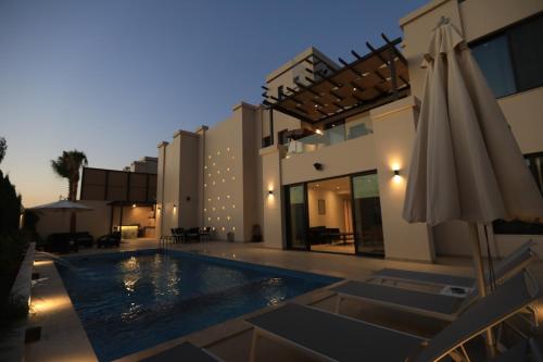 a house with a swimming pool and an umbrella at Zerø Føur DeadSea in Sowayma