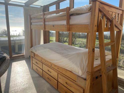 een houten stapelbed in een kamer met een raam bij The Old Lookout in Osmington