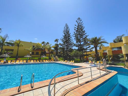 a large swimming pool with chairs and a resort at Seaside Apartment Corralejo : A cozy holiday home in a peaceful well located green complex in Corralejo