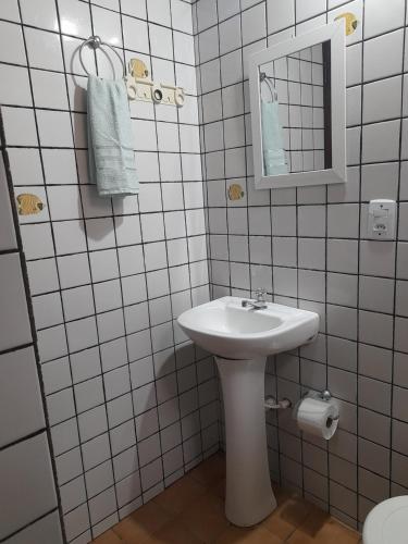 Baño blanco con lavabo y espejo en Chalés do Inglês, en Ilhabela