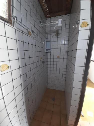uma casa de banho com um chuveiro com paredes em azulejos brancos em Chalés do Inglês em Ilhabela