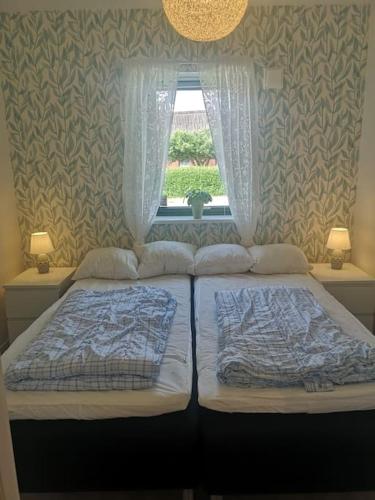 two beds in a bedroom with a window at Nybyggd marklägenhet strax utanför Torekov! in Båstad