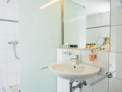 a white bathroom with a sink and a shower at Hotel Rhyhof in Frauenfeld