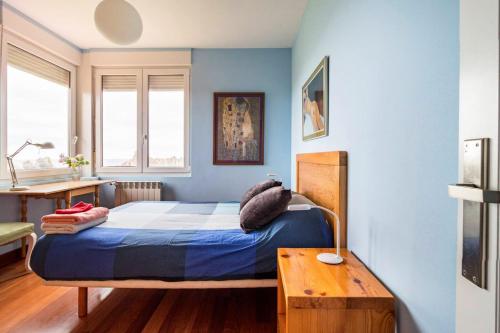 um quarto com uma cama com paredes azuis e uma mesa em 5 bedrooms house at Liencres 50 m away from the beach with sea view sauna and enclosed garden em Liencres