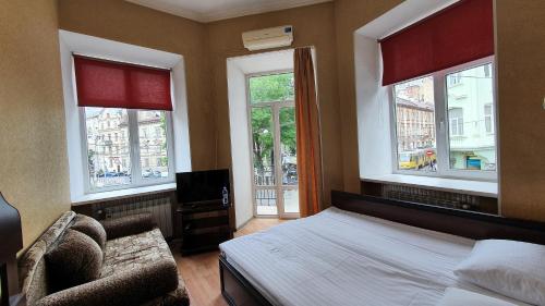 a bedroom with a bed and a chair and windows at Apart-Hotel City Center Contrabas in Lviv