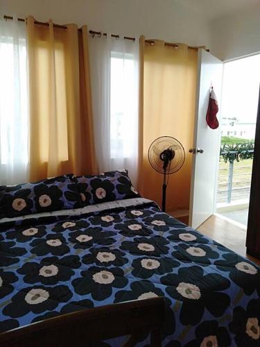 a bedroom with a bed with a blue comforter with flowers at Avida 3-Bedroom Vacation House with Pool in Minuluang