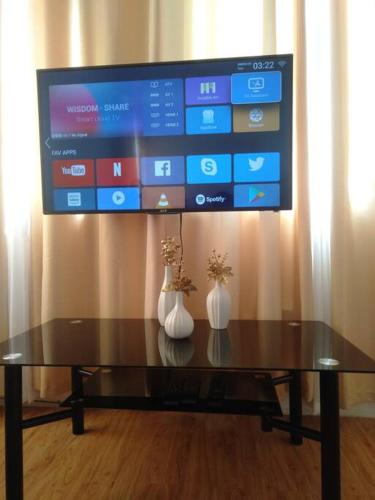 a tv sitting on top of a table with two vases at Avida 3-Bedroom Vacation House with Pool in Minuluang