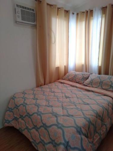 a bedroom with a bed and a window with curtains at Avida 3-Bedroom Vacation House with Pool in Minuluang