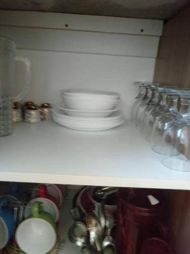 a shelf with dishes and other items on it at Avida 3-Bedroom Vacation House with Pool in Minuluang