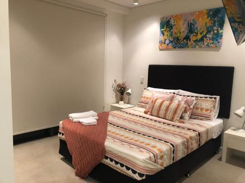 a bedroom with a bed and a painting on the wall at One-bed apartment at Darwin Waterfront Precinct in Darwin