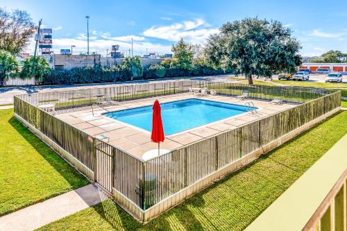 a swimming pool with a fence and a red umbrella at OYO Hotel Houston Southwest I-69 in Houston