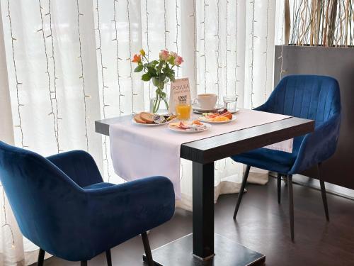 una mesa con un plato de comida y dos sillas azules en Hotel Modena en Bratislava