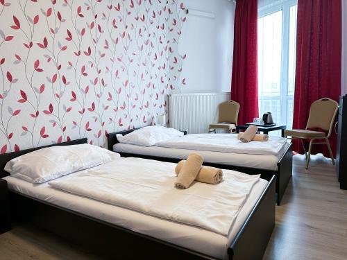 2 camas en una habitación con papel pintado rojo y blanco en Hotel Modena en Bratislava