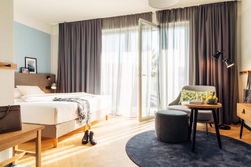 Pokój hotelowy z łóżkiem i krzesłem w obiekcie harry's home hotel & apartments w Villach