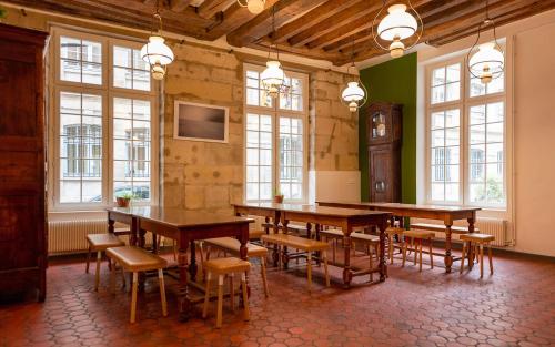 a large room with tables and chairs and a clock at MIJE MARAIS Hostel in Paris