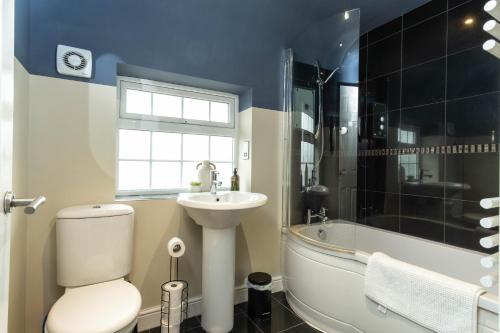 a bathroom with a toilet and a sink and a tub at Flamingo Retreat in Leicester