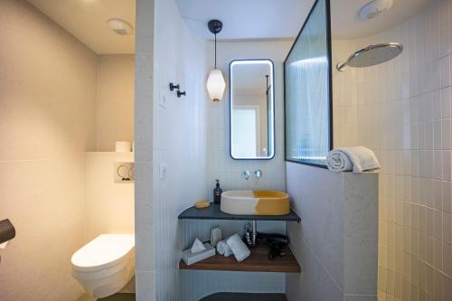 a bathroom with a sink and a toilet and a mirror at Hôtel du Parc Cavalaire sur Mer in Cavalaire-sur-Mer