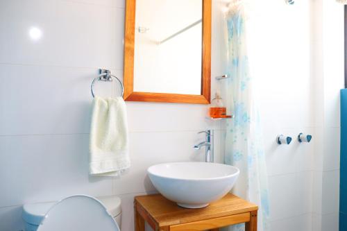 a bathroom with a sink and a mirror and a toilet at Hotel Casa Mandarine , Amazing Private Rooms w Balcony, Rooftop, Hammocks, AC, SmarTV, 100mbs! in Zihuatanejo