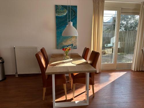 een eettafel met stoelen en een schilderij bij Duinerei appartement C001 in Callantsoog