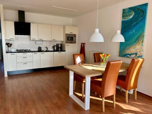 een keuken en eetkamer met een tafel en stoelen bij Duinerei appartement C001 in Callantsoog