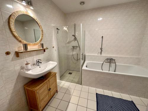 ein Badezimmer mit einem Waschbecken, einer Badewanne und einem Spiegel in der Unterkunft Duinerei appartement C001 in Callantsoog
