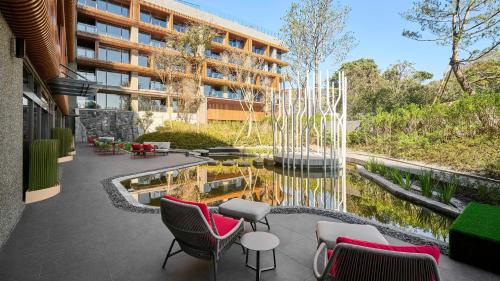 番路鄉的住宿－阿里山英迪格酒店，一座建筑前的庭院,配有椅子和池塘